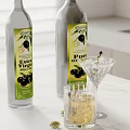 Extra Virgin And Pura Olive Oil Bottles With Glass Of Olives On White Countertop