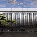Modern Metallic Feature Wall With Vertical Stripes Green Pine And Water Feature Under Blue Sky