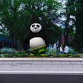 Large Panda Statue In Park With Green Trees And People Walking By
