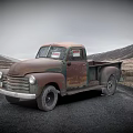 Rusty Old Truck Parked on Asphalt Road Against Mountainous Landscape and Cloudy Sky