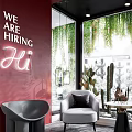 Modern Window Display with Red Wall Hanging Green Vines Cacti Gray Armchairs and Round Table