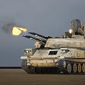 Military Tank With Radar System Firing Cannons Ejecting Flames On Desert Terrain