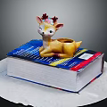 Colorful Thick Book With Decorative Lying Deer Figurine And Flower Decoration On Head