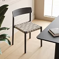 Modern Black Dining Chair With Woven Seat Next To Black Table And Green Plant