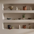 Various Ceramic Vessels Displayed on Built in Shelves with Beige Wall Potted Plant and Dried Flowers