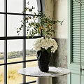 Textured Black Vase With White Hydrangeas And Green Foliage On Marble Table By Large Window