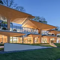 Modern Sales Office Building With Layered Roof Design And Illuminated Exterior Surrounded By Greenery