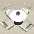 Modern Round Table White Top Black Base And Four Cushioned Ivory Chairs With Small Plant