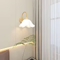 White Petal Shaped Wall Sconce with Warm Light by Window Near Gray Curtain and Potted Plant
