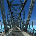 Steel Truss Bridge Spanning Water With Concrete Piers Against Blue Sky