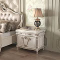 Ornate White Nightstand With Table Lamp And Books In Classic Bedroom With Floral Wallpaper