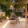 Beautiful Garden Featuring Wooden Bench Lush Green Plants Trees Purple Flowers And Hanging Lanterns