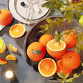 Fresh Oranges In Wooden Bowl With Sliced Oranges And Green Leaves