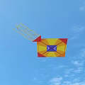 Yellow Red and Purple Geometric Kite Flying in Blue Sky with White Clouds