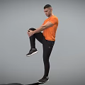 Man Standing on One Leg Holding Knee in Orange T-shirt Black Pants Sneakers Gray Background