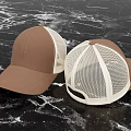 Two Brown Solid Color and White Mesh Hats Displayed on Black Marble Background 3d model