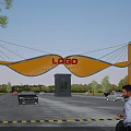 Scenic Modern Entrance Gate With Yellow Curved Design EAGLE Sign And Cars Trees Around