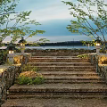 Stone Steps Landscape with Stone Walls Illuminated Lanterns and Greenery by Water at Twilight