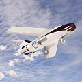 White and Dark Brown Passenger Plane With Blue Circular Logo Flying In Sky With Clouds