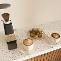 Coffee Grinder With Coffee Beans Latte Art Coffee Cups And Pastries On Speckled Countertop