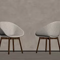 Two Modern Dining Chairs with Beige Upholstered Curved Backrest and Wooden Legs Against Light Wall