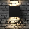 Black Square Wall Lamp Mounted On Brick Wall Illuminating Wall Surface And MY SHOP Letters