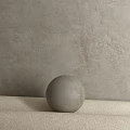 Gray Textured Sphere Component Placed On Light Colored Surface Against Textured Gray Wall