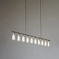 Linear Chandelier With Multiple Glass Shades Hanging On Long Metal Bar Against Light Wall