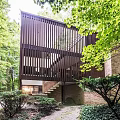 Dark Brown Wooden Detached House Surrounded by Lush Green Trees and Open Design