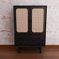 Black Entryway Console Cabinet With Woven Doors And Drawers Against Textured Wall On Wooden Floor