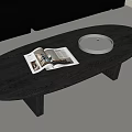 Modern Black Oval Coffee Table With Open Magazine White Tray Glass Cups Near Gray Sofa