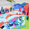 Colorful Children's Play Area With Slides Mushroom Decorations Wave Structures Green Lawn And Transparent Roof