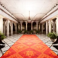 Grand Architectural Interior With Red Carpet Columns Symmetric Plants And High Ceiling