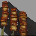 Three Roasted Pork Belly Skewers On Black Slate Plate With Glossy Surface