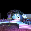 Elegant Banquet Hall Setup With Staged Platform Floral Decorations And Ambient Lighting