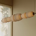 Modern Linear Pendant Light With Multiple Cream Paper Shades In Room With Window Blinds