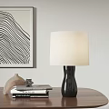Black Ceramic Base White Fabric Shade Table Lamp On Wooden Table With Abstract Art
