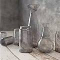 Ceramic Vessels In Various Shapes On Wooden Table With Gray Textured Wall And Natural Light
