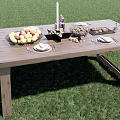 Outdoor Wooden Dining Table With Fruit Basket Candle Plates And Cutlery On Grass
