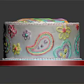 White Round Cake With Colorful Rainbow Flower Paisley Designs And Red Border On Reflective Plate