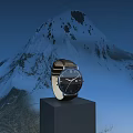 Elegant Watch On Black Cube Pedestal Against Snowy Mountain Blue Sky