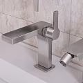 Sleek Modern Bathroom Faucets On White Countertop With Beige Tile Backdrop