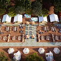 Scenic Outdoor Campsite With White Tents Dining Tables And Umbrellas Surrounded By Trees
