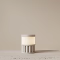 Minimalist Cylindrical Table Lamp with Striped Base White Lampshade on Light Table Against Beige Wall