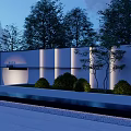 Modern Feature Wall With Illuminated Panels And Surrounding Greenery At Night