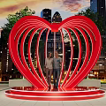 Red Heart Shaped Sculpture With Two People And City Night Skyline