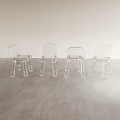 Four Clear Acrylic Leisure Chairs Placed On Gray Floor Against Light Colored Wall