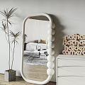 Oval Shaped Mirror With White Spherical Accents Wooden Letters And Palm Plant In Living Room