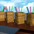 Four Golden Carved Decorative Pen Holders With Colored Pencils On Wooden Table