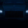 Luxury Rolls Royce Sedan Parked On Brick Pavement With Evening City Streetlights And Water Reflections